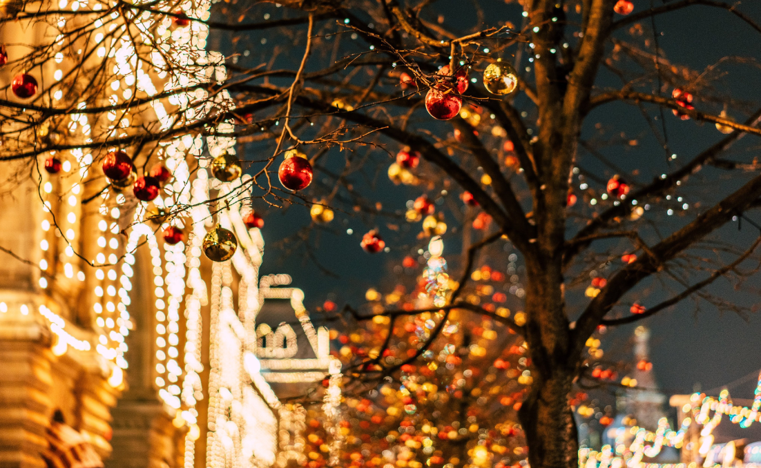 Rua de uma cidade pequena enfeitada com decorações de natal e com foco em uma árvore de ntal
